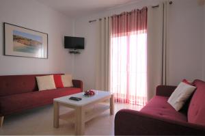 una sala de estar con 2 sofás rojos y una mesa. en Vila Mar Praia - Free wifi - 50 m From the beach, en Armação de Pêra