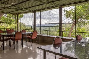 um restaurante com mesas e cadeiras e uma grande janela em KSTDC Hotel Mayura Nisarga Pearl Valley em Anekal