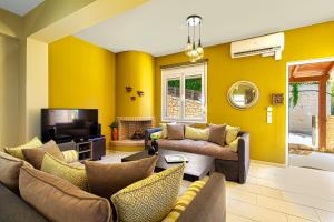 uma sala de estar com paredes amarelas e sofás e uma televisão em Theo Villas em Marathokefála