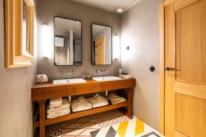 a bathroom with two sinks and two mirrors at Hotel La Torre del Canonigo - Small Luxury Hotels in Ibiza Town