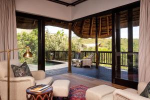 a living room with a view of a pool and a patio at Lalibela Game Reserve - Kichaka Lodge in Paterson