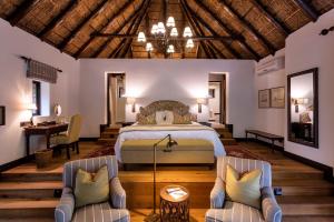 Lalibela Game Reserve - Kichaka Lodge في باترسون: غرفة نوم بسرير وكرسيين