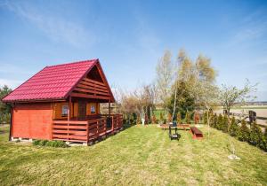 een kleine hut met een rood dak in het gras bij Dom Koprowo in Międzywodzie