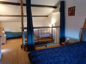 um quarto com uma cama com cortinas azuis em La Pierre du Grain em Ravel