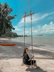 une femme assise sur une balançoire sur la plage dans l'établissement Grand Sea Beach Resort, à Haad Pleayleam