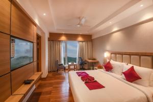Pokój hotelowy z dużym łóżkiem i telewizorem w obiekcie Emerald Clarks Inn Suites w mieście Mysuru