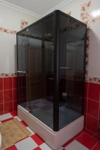 a glass shower in a bathroom with red tiles at Versal Hotel in Maykop