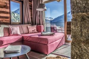 a living room with a pink couch and a table at Chalets - The Peak in Sölden
