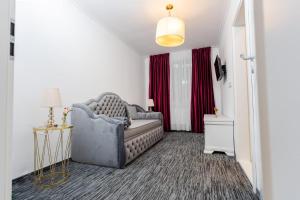 a living room with a gray couch and red curtains at Apartament Carolyne in Bistriţa