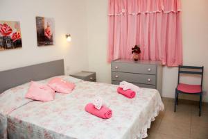 um quarto com duas almofadas cor-de-rosa numa cama em Fiesta Apartment Seaview em Mellieħa