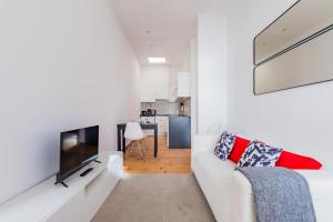 ein Wohnzimmer mit einem weißen Sofa und einem TV in der Unterkunft LX Urban Living in Lissabon