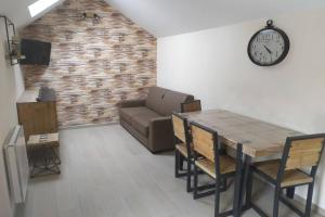 ein Wohnzimmer mit einem Tisch, einem Sofa und einer Uhr in der Unterkunft chalet avec jardin proche du Mont Saint Michel in Pontorson
