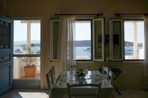 a dining room with a table and chairs and windows at Exohiko in Aliki +27 photos