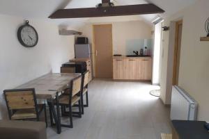 a kitchen with a table and a clock on the wall at chalet avec jardin proche du Mont Saint Michel in Pontorson