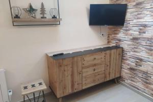 une télévision sur un mur avec une armoire en bois dans l'établissement chalet avec jardin proche du Mont Saint Michel, à Pontorson