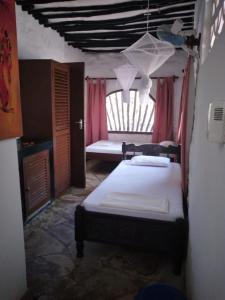 um quarto com uma cama num quarto com uma janela em Diani Banda Cottages em Diani Beach