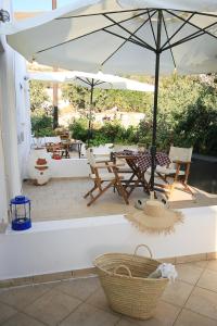 a patio with an umbrella and chairs and tables at Kallichoron Country Houses in Astypalaia Town