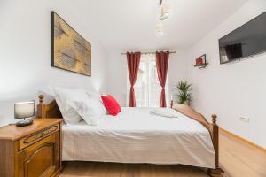 a bedroom with a bed with white sheets and red pillows at Studio Roberta Coressi in Braşov