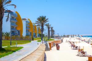 a beach with chairs and palm trees and buildings at Dpto de playa en Paracas in Paracas
