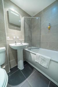 a bathroom with a sink and a tub and a toilet at Widnes Halton Everglades Park Hotel in Widnes