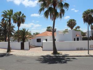 una casa blanca con palmeras delante en Villa La Charlatana en Caleta de Fuste