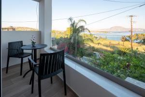 a balcony with two chairs and a table and a large window at Eleftherias Suites - Near Beach Apartments in Marathi