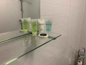 a glass shelf in a bathroom with three bottles of moisturizers at Station Lodge - FREE off-site Health Club access with Pool, Sauna, Steam Room & Gym in Windermere