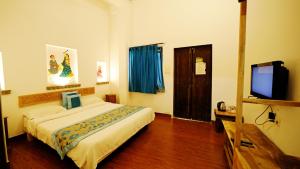 Habitación de hotel con cama y TV de pantalla plana. en Udaigarh - Udaipur, en Udaipur