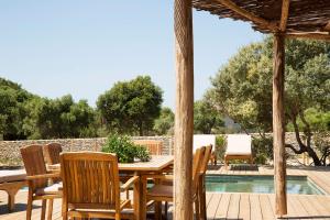 a wooden table and chairs next to a swimming pool at U Capu Biancu in Bonifacio