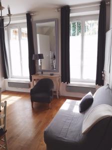 a living room with a couch and a chair and a mirror at Le Petit Mansart in Versailles