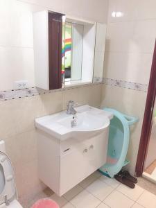 a bathroom with a sink and a toilet and a mirror at Funny Eggs Guest House in Tainan