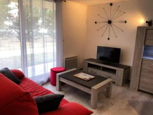 a living room with a red couch and a tv at Residence Le Sequoia - maeva Home in Bolquere Pyrenees 2000