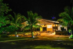 ein Restaurant mit Tischen und Palmen in der Nacht in der Unterkunft Pousada 3 Reis in Olímpia