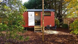 a red tiny house with a table and chairs at Forest Heath Shepherd's Hut in Ringwood