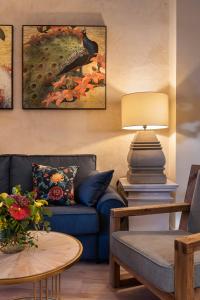 a living room with a blue couch and a bird painting at Casa Sevilla 1855 Suites by Época in Seville