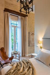 a bedroom with a bed and a chair and a window at Casa Sevilla 1855 Suites by Época in Seville