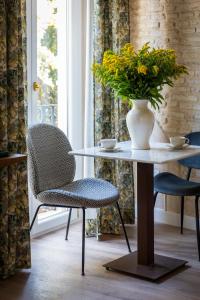 a table and chair with a vase of flowers on it at Casa Sevilla 1855 Suites by Época in Seville