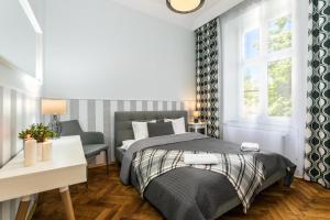 a bedroom with a bed and a desk and window at Exclusive Royal Apartments in Krakow