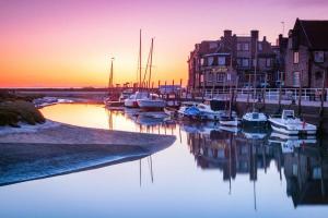 a group of boats docked in a marina at sunset at Blakeney Norfolk Bramble Lodge ***Self Catering*** in Blakeney