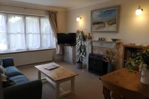 a living room with a couch and a tv and a table at Blakeney Norfolk Bramble Lodge ***Self Catering*** in Blakeney