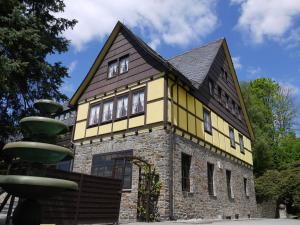 ein gelbes und schwarzes Haus mit einem Brunnen in der Unterkunft Parkhotel Schwarzenberg - Garni in Schwarzenberg