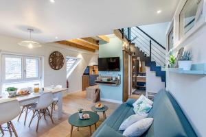 ein Wohnzimmer und eine Küche mit einem blauen Sofa und einem Tisch in der Unterkunft Gîte La Rodernelle - Sauna privatif - Climatisation - Vue sur le Château du Haut Kœnigsbourg in Rodern
