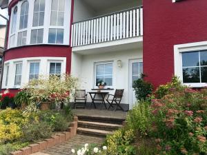 a red and white house with a table and some flowers at Ferienwohnung Kaspers in Schalkenmehren