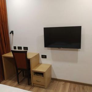 Camera con scrivania e TV a schermo piatto a parete. di PPH Living Railotel Coimbatore a Coimbatore