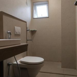 a bathroom with a toilet and a sink and a window at PPH Living Railotel Coimbatore in Coimbatore +8 photos