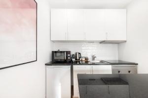 uma cozinha branca com um lavatório e um micro-ondas em Yolo Apartment by Olala Homes em Cascais