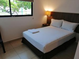 - une chambre avec un grand lit blanc et une fenêtre dans l'établissement Buenavista Place Hotel, à Bahía de Caráquez