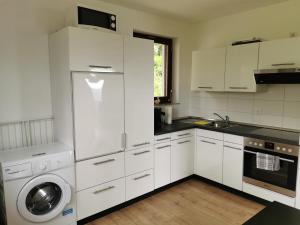 a kitchen with white cabinets and a washing machine at Ferienhaus Nele in Hilders