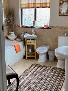 uma casa de banho com uma banheira, um WC e um lavatório. em Orchard Side Bed and Breakfast em Great Malvern