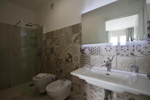 a bathroom with a sink and a toilet and a mirror at La Guitgia Rooms in Lampedusa